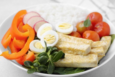Photo of Delicious poke bowl with basil, vegetables, eggs and tofu on light grey table, closeup