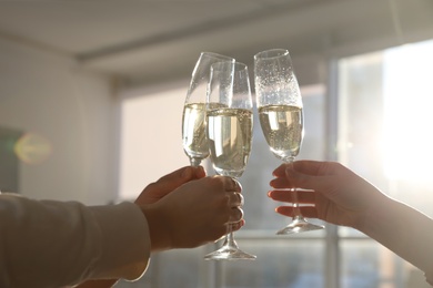 People clinking glasses of champagne in office, closeup. Holiday cheer and drink