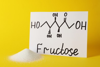 Photo of Pile of sugar and word Fructose with drawn scheme on paper against yellow background