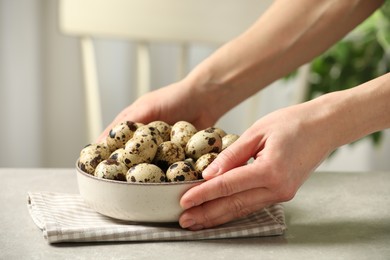 Photo of Woman with bowl of quail eggs at table indoors, closeup