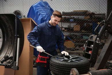 Technician working with car wheel at automobile repair shop
