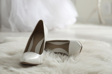 White wedding shoes on furry rug in room