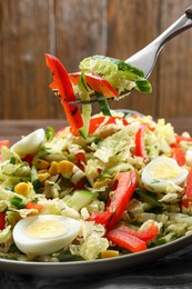 Photo of Fork of delicious salad with Chinese cabbage and quail eggs above plate, closeup