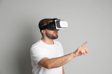 Man using virtual reality headset on light grey background