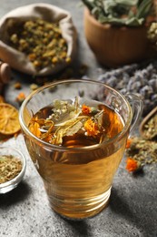 Freshly brewed tea and dried herbs on grey table