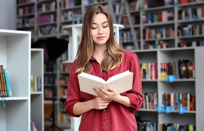 Young woman reading book in modern library