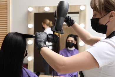 Photo of Professional stylist working with client in beauty salon. Hairdressing services during Coronavirus quarantine