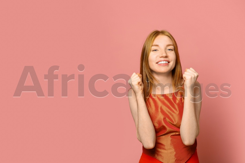 Portrait of happy young woman on pink background, space for text