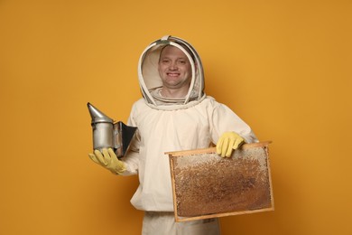 Beekeeper in uniform holding smokepot and hive frame with honeycomb on yellow background