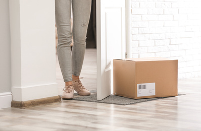 Woman in doorway and parcel on rug, closeup. Delivery service
