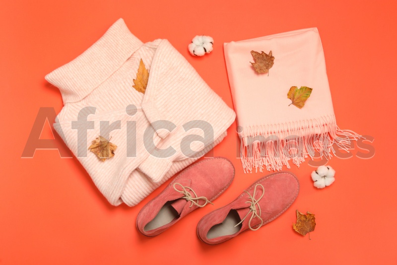 Photo of Flat lay composition with sweater and dry leaves on orange background. Autumn season