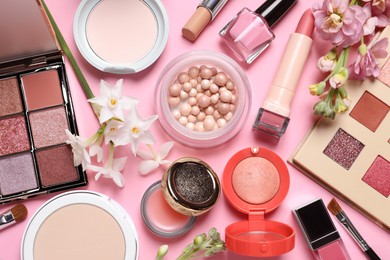 Photo of Flat lay composition with different makeup products and beautiful flowers on pink background