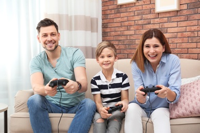 Happy family playing video games on sofa in living room