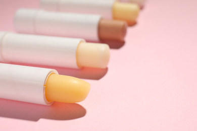 Hygienic lipsticks on pink background, closeup view