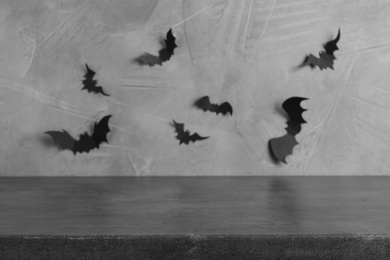Stone table near grey wall with black paper bats. Halloween decoration