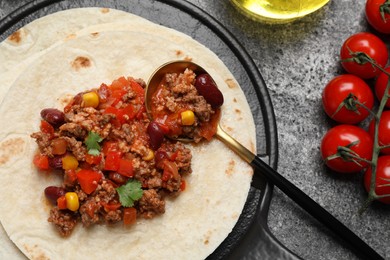 Tasty chili con carne with tortilla and tomatoes on grey table, flat lay