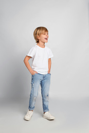 Happy little boy in casual outfit on light grey background
