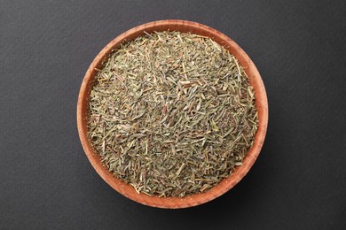 Wooden bowl with dried thyme on grey background, top view