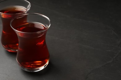 Photo of Glasses with traditional Turkish tea on black table, closeup. Space for text