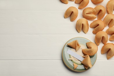Photo of Tasty fortune cookies and paper with prediction on white wooden table, flat lay. Space for text