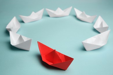 Photo of Group of paper boats following red one on light background. Leadership concept