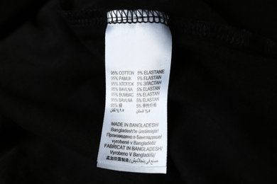 Clothing label with material content on black shirt, closeup view