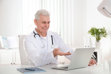 Doctor consulting patient using video chat on laptop in clinic