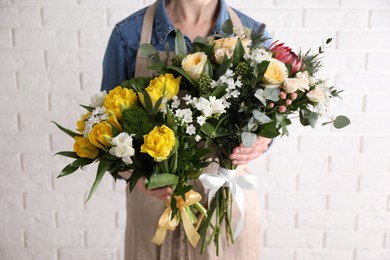 Woman with beautiful bouquets near white brick wall, closeup