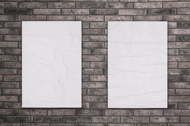 Blank creased posters on grey brick wall. Mockup for design 