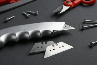 Utility knife with blades among other tools on grey background
