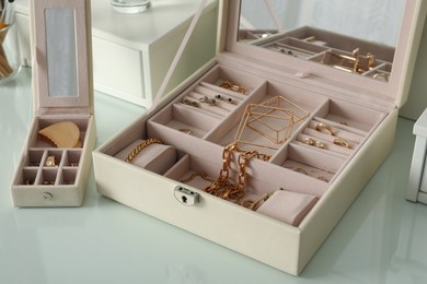 Jewelry boxes with stylish golden bijouterie on white dressing table