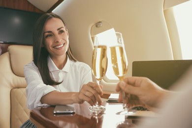 Colleagues clinking glasses of champagne at table in airplane during flight