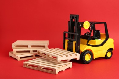 Toy forklift and wooden pallets on red background