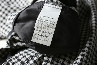 Clothing label with size and care instructions on checkered garment, closeup