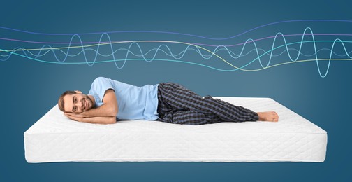 Happy man lying on mattress against blue background. Healthy circadian rhythm and sleep habits