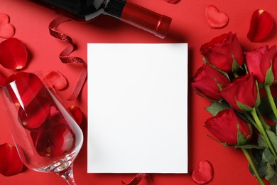Flat lay composition with blank greeting card, wine and roses on red background. Valentine's day celebration