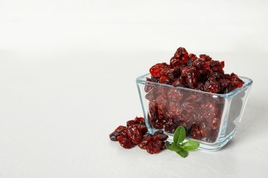 Tasty dried cranberries and leaves on white table. Space for text