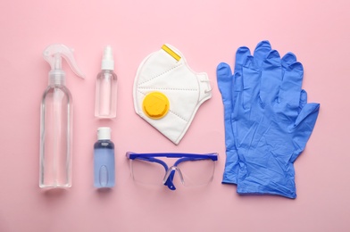 Flat lay composition with medical gloves, mask and hand sanitizers on pink background