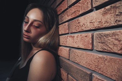 Overdosed drug addicted woman near brick wall. Space for text