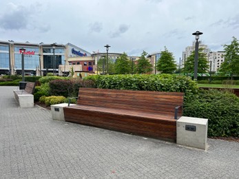 Photo of Alley with wooden benches, power sockets and beautiful plants near shopping mall