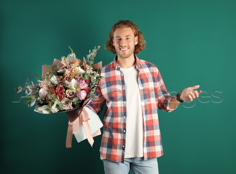 Young handsome man with beautiful flower bouquet on green background