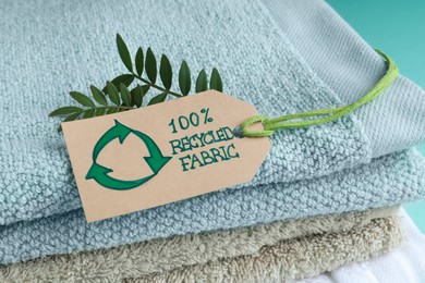 Stacked towels with recycling label and plant, closeup