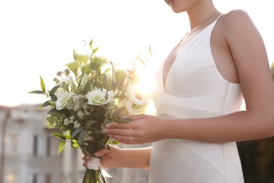 Bride in beautiful wedding dress with bouquet outdoors, closeup