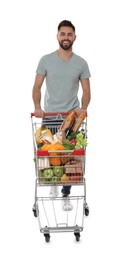 Happy man with shopping cart full of groceries on white background