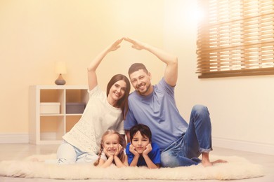 Happy family forming house roof with their hands at home. Insurance concept