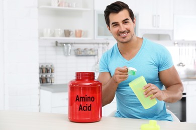 Young athletic man preparing amino acids drink in kitchen