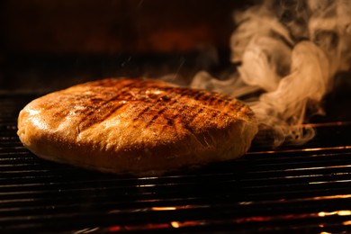 Photo of Baking pita bread on grilling grate in oven, closeup