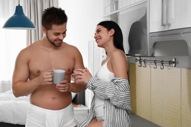 Young couple in white underwear drinking coffee at home