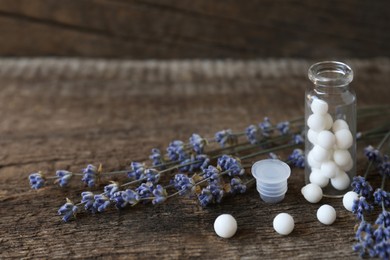 Bottle with homeopathic remedy and lavender flowers on wooden table. Space for text