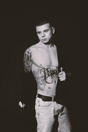 Image of Young man with tattoos on dark background. Black and white photography